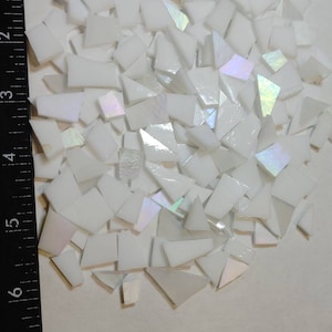 May include: A pile of white iridescent glass tiles, some are square and some are triangular, with a ruler in the background.