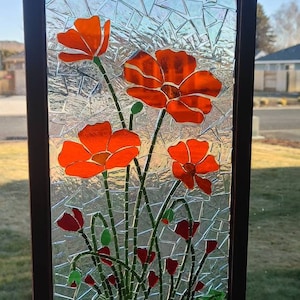 Puede incluir: Panel de vidrieras con amapolas de color naranja brillante y hojas verdes. El panel est&aacute; enmarcado en un borde marr&oacute;n oscuro e incluye el texto "This is GOG (glass on glass) Using cathedral glass. Glass that light can be seen through."