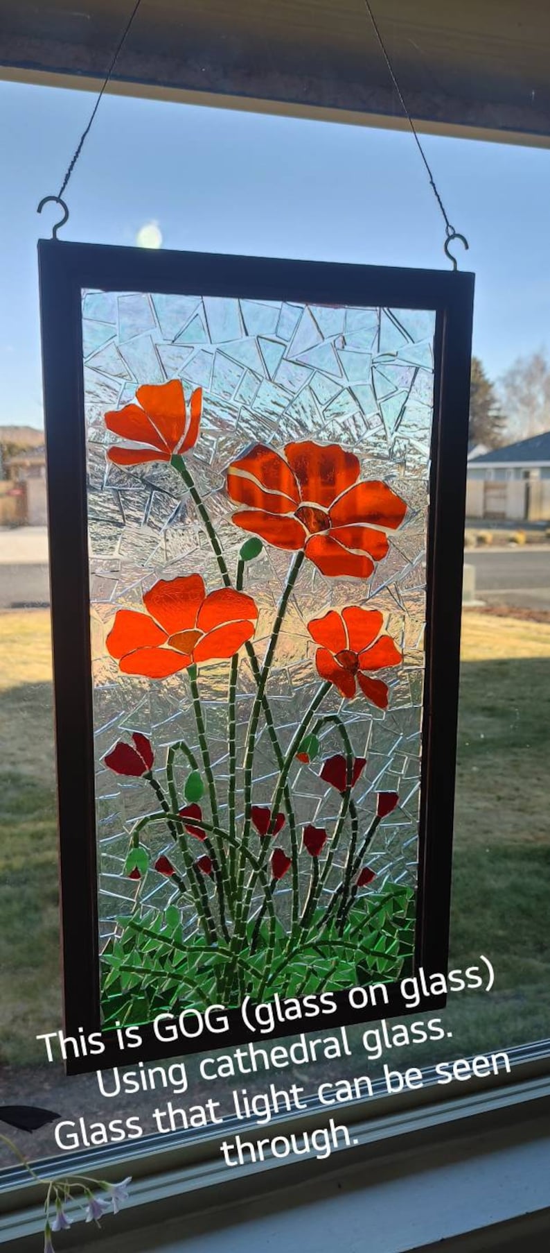 Puede incluir: Panel de vidrieras con amapolas de color naranja brillante y hojas verdes. El panel est&aacute; enmarcado en un borde marr&oacute;n oscuro e incluye el texto "This is GOG (glass on glass) Using cathedral glass. Glass that light can be seen through."