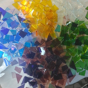 Puede incluir: Una colecci&oacute;n de coloridas teselas de mosaico de vidrio en tonos amarillo, azul, verde y morado. Las teselas est&aacute;n dispuestas en un patr&oacute;n semicircular. El texto "debscolorfulcorner" es visible.