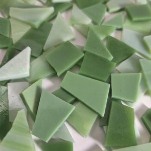 May include: A collection of green glass mosaic tiles in various shapes, including triangles and rectangles. The tiles range in shades from light to dark green, creating a textured and layered effect. The Etsy shop name "Debscolorfulcorner.etsy.com" is visible in the image.
