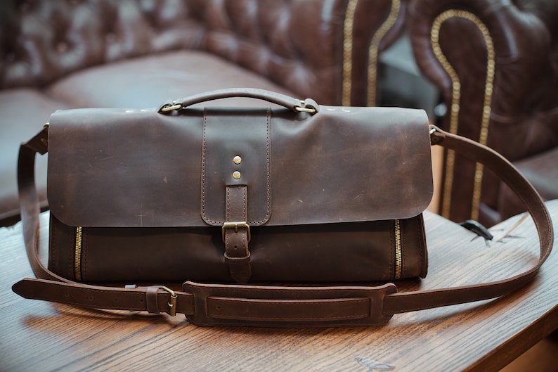 Brown leather doctor bag with brass snap and adjustable strap with shoulder pad