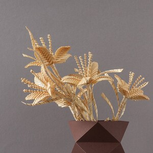 May include: A brown geometric vase with a bouquet of dried, light brown, straw-like flowers.