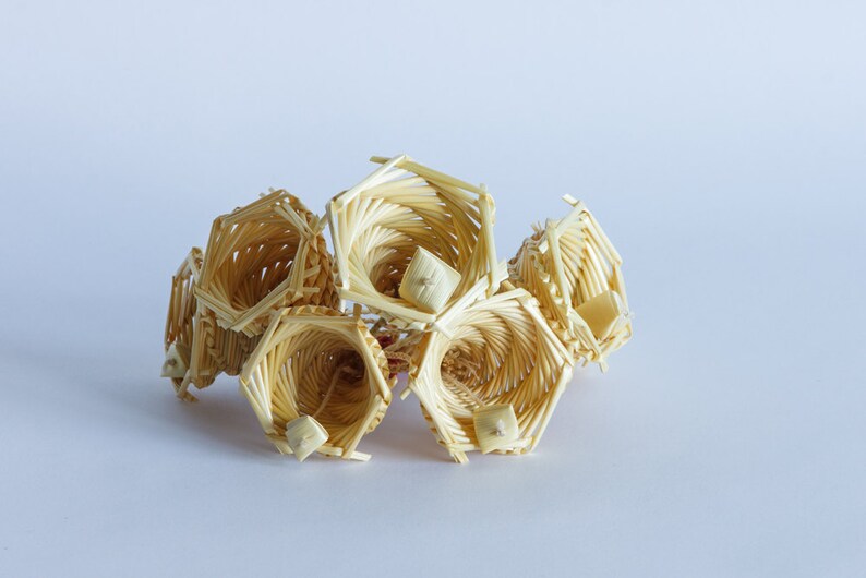 May include: A cluster of woven straw bells, each with a distinctive shape and texture. The bells are a light beige colour and have a natural, rustic appearance.
