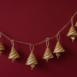 May include: A string of seven small, woven, beige Christmas tree decorations hanging on a red background.