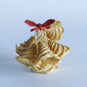 May include: A small, intricately woven straw ornament with a red crocheted bow on top. The ornament is shaped like a bell or a flower.