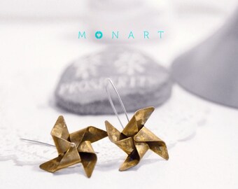 May include: A pair of gold-toned earrings shaped like pinwheels. The earrings are made of metal and have a rustic, vintage look.