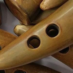 May include: A group of brown horn buttons with two or three holes each. The buttons are in the shape of a pointed oval.