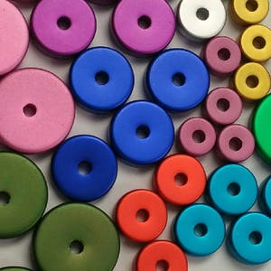 May include: Assortment of colorful round metal beads with a hole in the center. The beads are various shades of green, blue, red, pink, and gold.