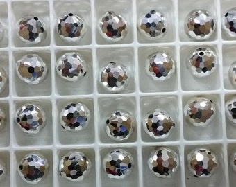 May include: A close-up of a white plastic container filled with 24 silver-colored faceted beads. The beads are arranged in a grid pattern.