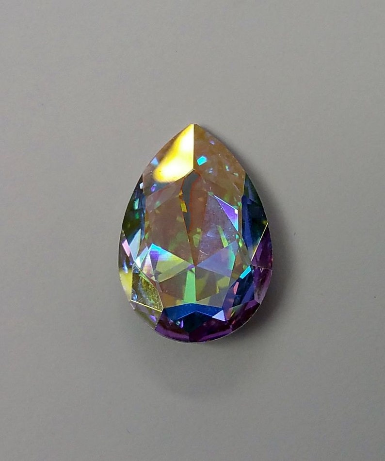Peut inclure: Un cristal iridescent en forme de larme avec un arc-en-ciel de couleurs, y compris le violet, le bleu, le vert et l'or.