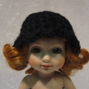 May include: A doll with red curly hair wearing a black crocheted hat.