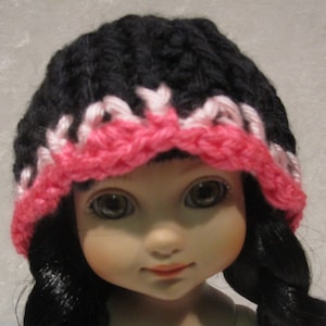 May include: Black knit hat with a pink and white crocheted trim. The hat is worn by a doll with black hair.
