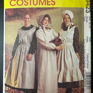 May include: A vintage sewing pattern for three dresses, featuring a white, black, and floral print. The pattern is for sizes 8-10 and is called "McCall's Costumes 9423".