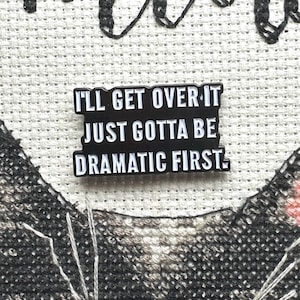 May include: Black and white enamel pin with the text "I'll get over it, just gotta be dramatic first."
