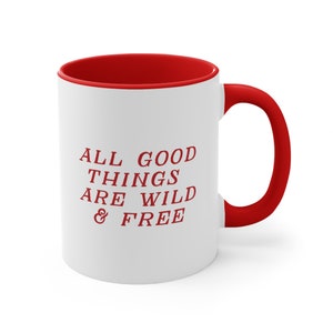 May include: White ceramic mug with a red rim and handle. The mug has the text "ALL GOOD THINGS ARE WILD & FREE" printed in red.