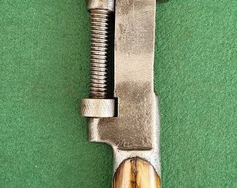 Puede incluir: Una llave inglesa ajustable vintage con mango de madera. La llave es de metal y tiene un acabado plateado. El mango es de madera y tiene un acabado marrón oscuro.