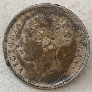Puede incluir: Una moneda de bronce con un perfil de cabeza de mujer mirando hacia la izquierda. La moneda tiene las palabras "VICTORIA REGINA" alrededor del borde.