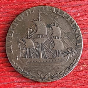 May include: A copper coin with the inscription "Le Vaisseau De L'Alpe" and a detailed image of a ship with sails.