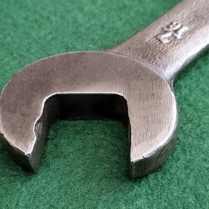 K&ouml;nnte beinhalten: Nahaufnahme eines silbernen Schraubenschl&uuml;ssels mit einer abgerundeten &Ouml;ffnung. Der Schraubenschl&uuml;ssel hat die Nummer "24" auf dem Griff.