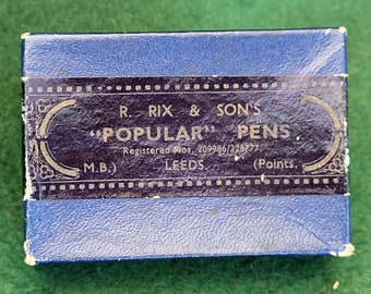 Könnte beinhalten: Eine blaue Schachtel mit einem goldenen und violetten Etikett, auf dem steht "R. RIX & SON'S "POPULAR" PENS Registered Nos. 209986/228777. LEEDS. (Points."