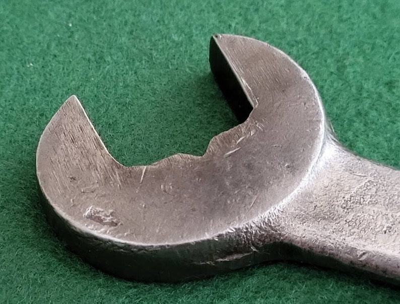 K&ouml;nnte beinhalten: Nahaufnahme eines silbernen Schraubenschl&uuml;ssels mit abgerundetem Kopf und leicht abgenutzter Oberfl&auml;che.