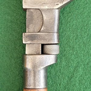 Puede incluir: Llave inglesa antigua con mango de madera. La herramienta de metal tiene una cabeza de martillo y el texto "P.S. & W. CO. CLEVELAND, O." es visible. La llave inglesa está sobre un fondo verde.