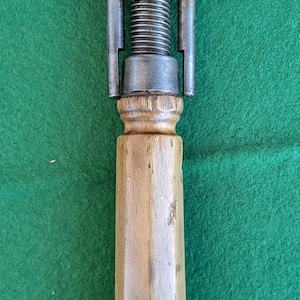 Peut inclure: Une pince métallique vintage avec un manche en bois. La pince est dotée d'une tige filetée pour régler les mâchoires. La poignée est cylindrique et en bois clair. Les pièces métalliques montrent des signes d'âge et d'utilisation.