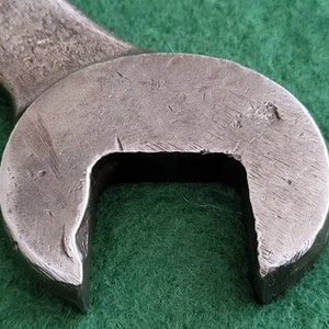 K&ouml;nnte beinhalten: Nahaufnahme eines silbernen Schraubenschl&uuml;ssels mit abgerundetem Kopf und einer quadratischen &Ouml;ffnung. Der Schraubenschl&uuml;ssel hat ein abgenutztes, gebrauchtes Aussehen.