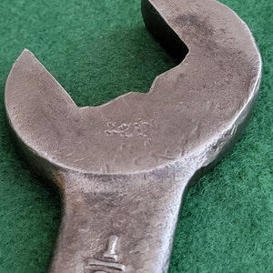 K&ouml;nnte beinhalten: Nahaufnahme eines silbernen Schraubenschl&uuml;ssels mit einer 1/2 Zoll Markierung. Der Schraubenschl&uuml;ssel liegt auf einer gr&uuml;nen Oberfl&auml;che.