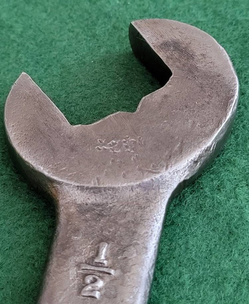 K&ouml;nnte beinhalten: Nahaufnahme eines silbernen Schraubenschl&uuml;ssels mit einer 1/2 Zoll Markierung. Der Schraubenschl&uuml;ssel liegt auf einer gr&uuml;nen Oberfl&auml;che.