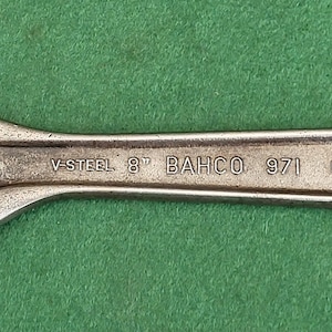 May include: A silver adjustable wrench with the text "V-STEEL 8" BAHCO 971 MADE IN SWEDEN" on the handle.