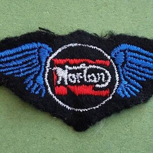 May include: Black fabric patch with blue wings and a red, white and blue circle with the word "Norton" in white lettering.