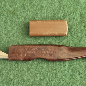 May include: A vintage brown map measurer with a metal wheel and a separate rectangular case. The text on the measurer reads: "FOR ANY SCALE MAPS EXAMPLE 1 IN. SCALE 4 CLICKS TO 1 MILE". The items are on a green surface.