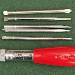 May include: A red handled screwdriver with a metal shaft and a textured grip collar, accompanied by four interchangeable metal screwdriver bits of varying tip styles. The handle features the white text PRINT SHEFFIELD ENGLAND.