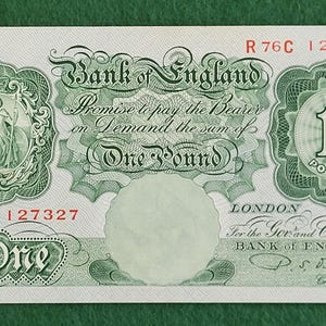 May include: A vintage Bank of England one-pound note. The note features intricate green designs, including a portrait, the text "Bank of England," and the promise to pay the bearer. The number "1" is prominently displayed.