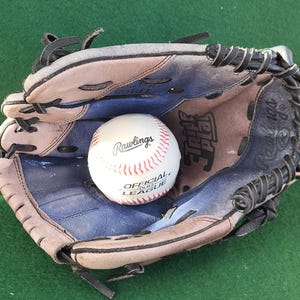 Peut inclure: Un gant de baseball marron, bleu et noir, contenant une balle de baseball blanche avec des coutures rouges. Le gant a des lacets noirs. La balle porte l'inscription "Rawlings Official League".