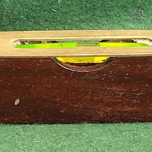 May include: A brass and wood level with a green bubble level. The level has the text "NEWBOLD & CO. LONDON" on the brass side.