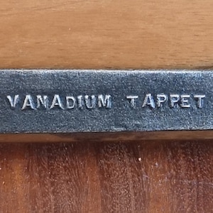 May include: A silver wrench with the text "VANADIUM - TAPPET" and the number "12" on the handle.