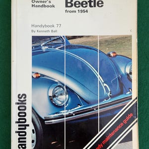 May include: A vintage "Beetle" owner's handbook from 1954. The cover features a blue car illustration with the text "Handybooks" and "Handy maintenance guide". The handbook is titled "Handybook 77" by Kenneth Ball.