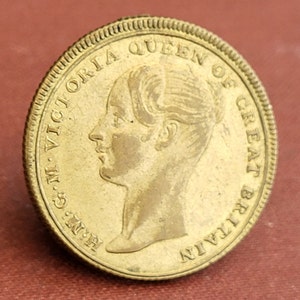 Puede incluir: Una moneda de color dorado con un perfil de la reina Victoria en el anverso. La moneda dice "G.M. VICTORIA QUEEN OF GREAT BRITAIN".