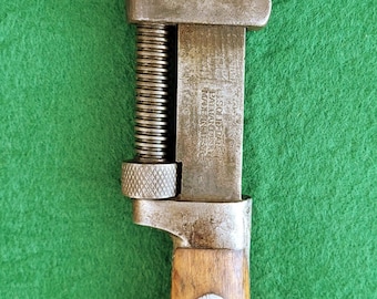 Puede incluir: Llave inglesa ajustable vintage con mango de madera. La llave, de metal, tiene el nombre "RUSSWIN" estampado en la parte superior. El mango está sujeto con dos remaches. El texto "SOLID BAR PAT. JAN. 96 MADE IN U.S.A." es visible.