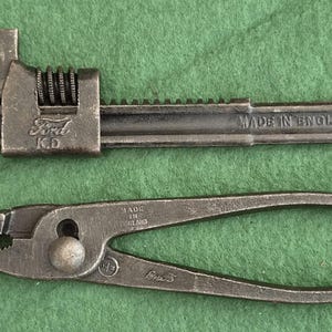 Op de afbeelding: Een donkergrijze metalen verstelbare moersleutel met de tekst Ford K.D. en Made in England in reliëf aan de zijkant, geplaatst boven een donkergrijze metalen combinatietang met de tekst Made in England in reliëf op het handvat.