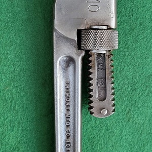 May include: A silver adjustable wrench with the text "TRIMO MFG CO ROXBURY MASS U.S.A." and "TRIMO 12" printed on the handle.