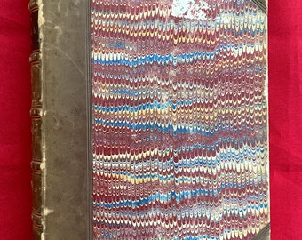 May include: A vintage book with a brown leather cover and marbled paper boards. The book has a spine with raised lettering and a decorative design on the front cover.