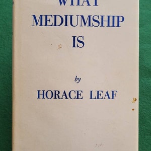 May include: A vintage book titled 'WHAT MEDIUMSHIP IS' by Horace Leaf. The cover is off-white with blue text. The book shows signs of wear and age.
