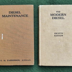 May include: Two vintage books on a green surface. The book on the left is titled "DIESEL MAINTENANCE" and the other is titled "THE MODERN DIESEL". The first book is brown and the second is beige. Both books have text printed in black.