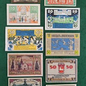 Puede incluir: Una colección de billetes o cupones de papel alemanes antiguos. Los billetes están impresos en papel grueso con ilustraciones y texto coloridos. Los billetes presentan diversas escenas, como una cordillera montañosa, un edificio y un grupo de personas bailando. Los billetes son de diferentes denominaciones, incluyendo 10, 20 y 50.