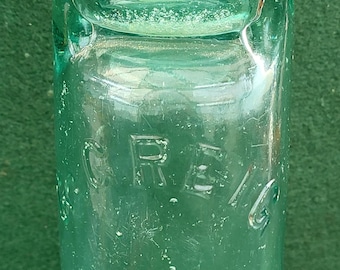 Puede incluir: Una botella de vidrio verde vintage con una parte superior redondeada y una etiqueta que dice "GREIG".