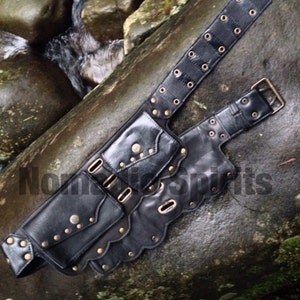 May include: Black leather belt with multiple pockets and decorative studs. The belt has a scalloped edge and is fastened with a buckle.